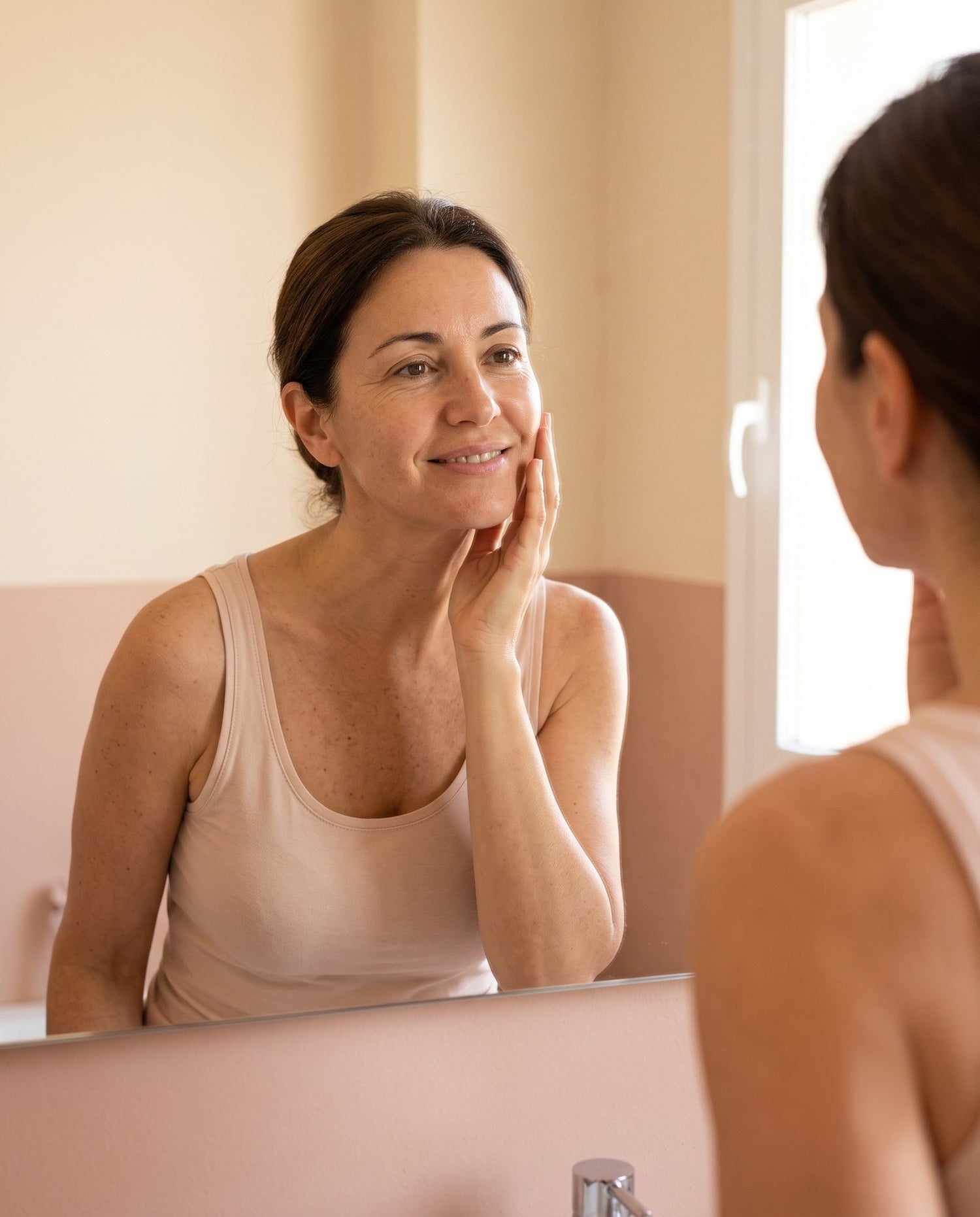 Mujer de mediana edad sonriendo frente al espejo por la mañana